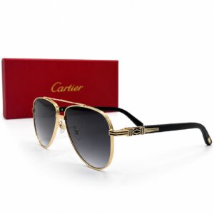Lunettes de soleil de luxe de style aviateur Première de Cartier avec monture en métal doré poli, double pont, verres gris dégradés et branches en acétate noir ornées d'un motif géométrique en émail noir et or, présentées à côté de leur écrin rouge signature Cartier.