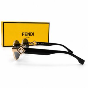 Lunettes de soleil de luxe Fendi FF Diamonds avec monture ronde en métal doré, branches épaisses en acétate noir ornées du logo FF doré, posées devant leur boîte jaune Fendi Roma.