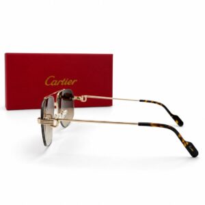 Lunettes de soleil Cartier haut de gamme pour homme avec monture percée dorée, double pont et verres dégradés marron, présentées devant leur boîte rouge emblématique.