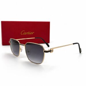 Lunettes de soleil de luxe Cartier avec monture en métal doré et liseré en laque noire, verres foncés et charnières dorées Signature C de Cartier, posées à côté de leur boîte rouge emblématique.